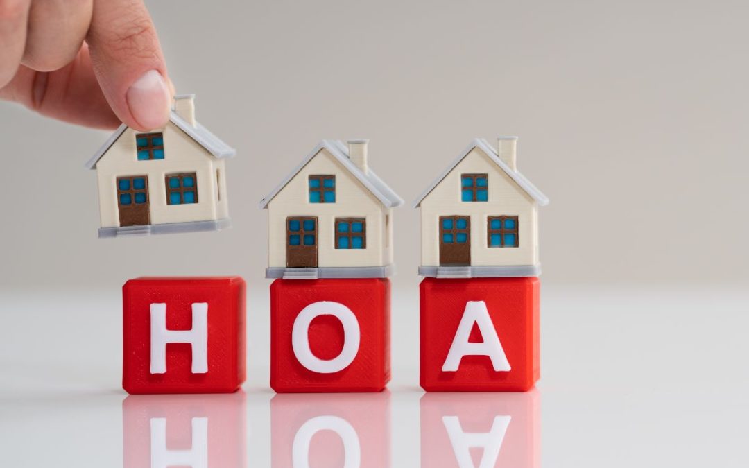 photo of red blocks reading: HOA and a hand placing miniature houses on top of them